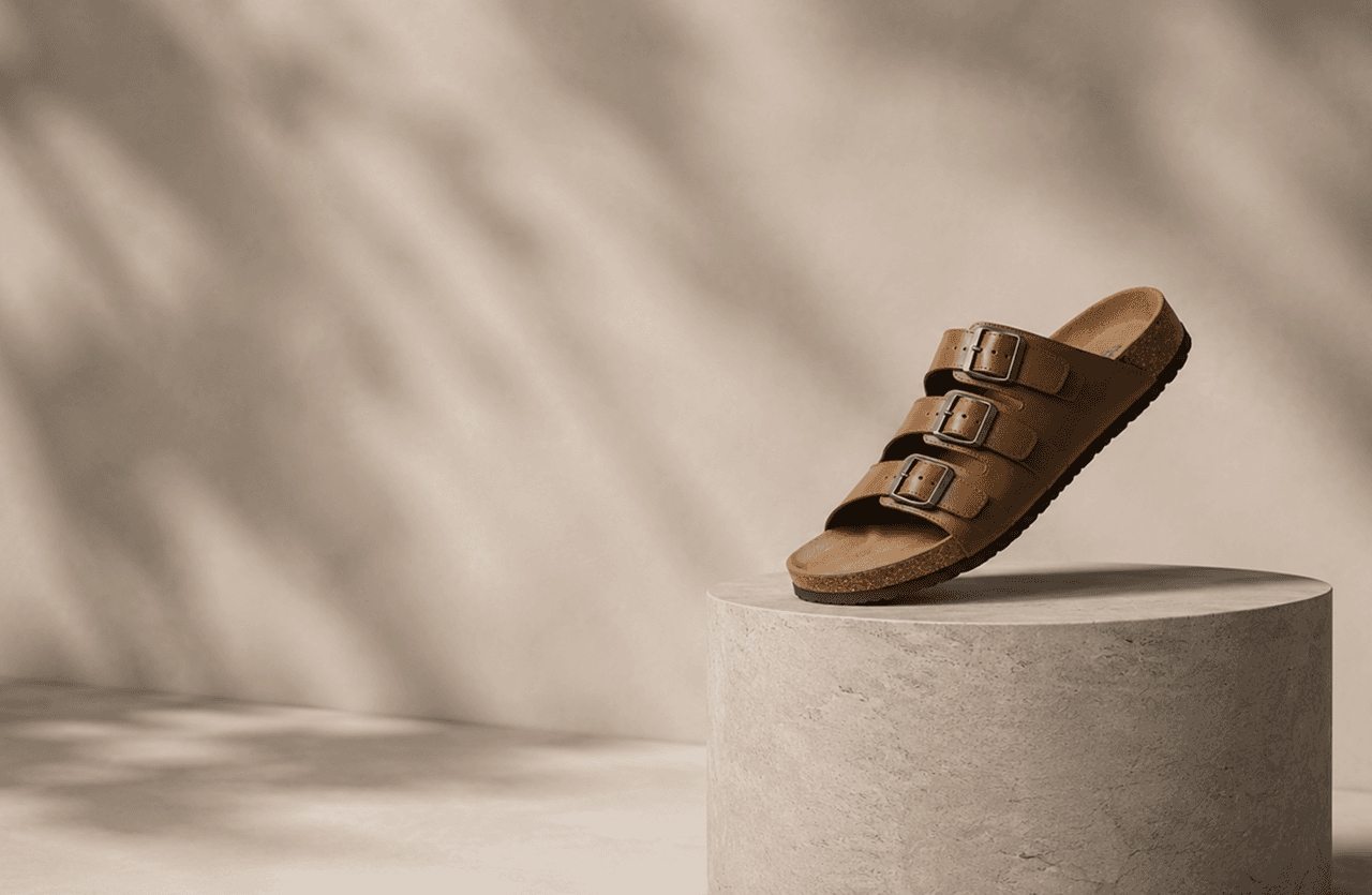 A tan leather Kaalcari slide resting on a stone plinth